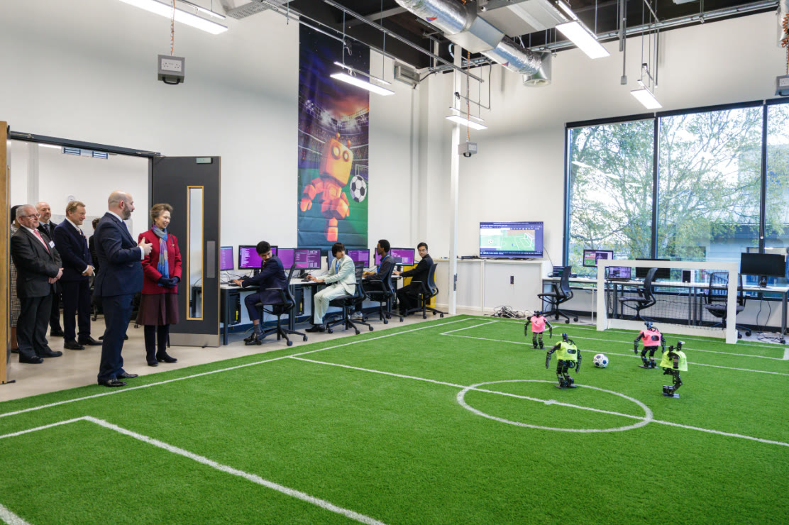 The Princess Royal and the official party watching four humanoid robots play football on the indoor pitch at Spectra